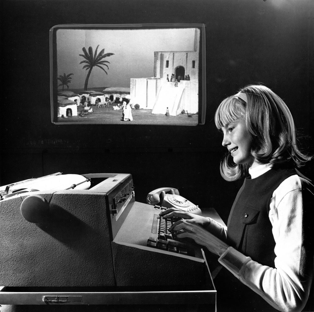 Učenica igra igricu na teleprinteru, s jednom od slika projektora u pozadini.